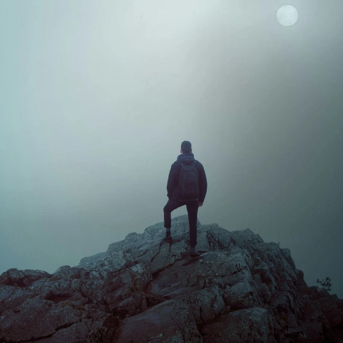 man in black jacket standing on rock formation during daytime